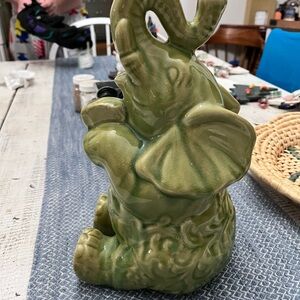 Elephant ceramic- Green Glaze Sitting with Floral Relief Design 10 1/2” euc